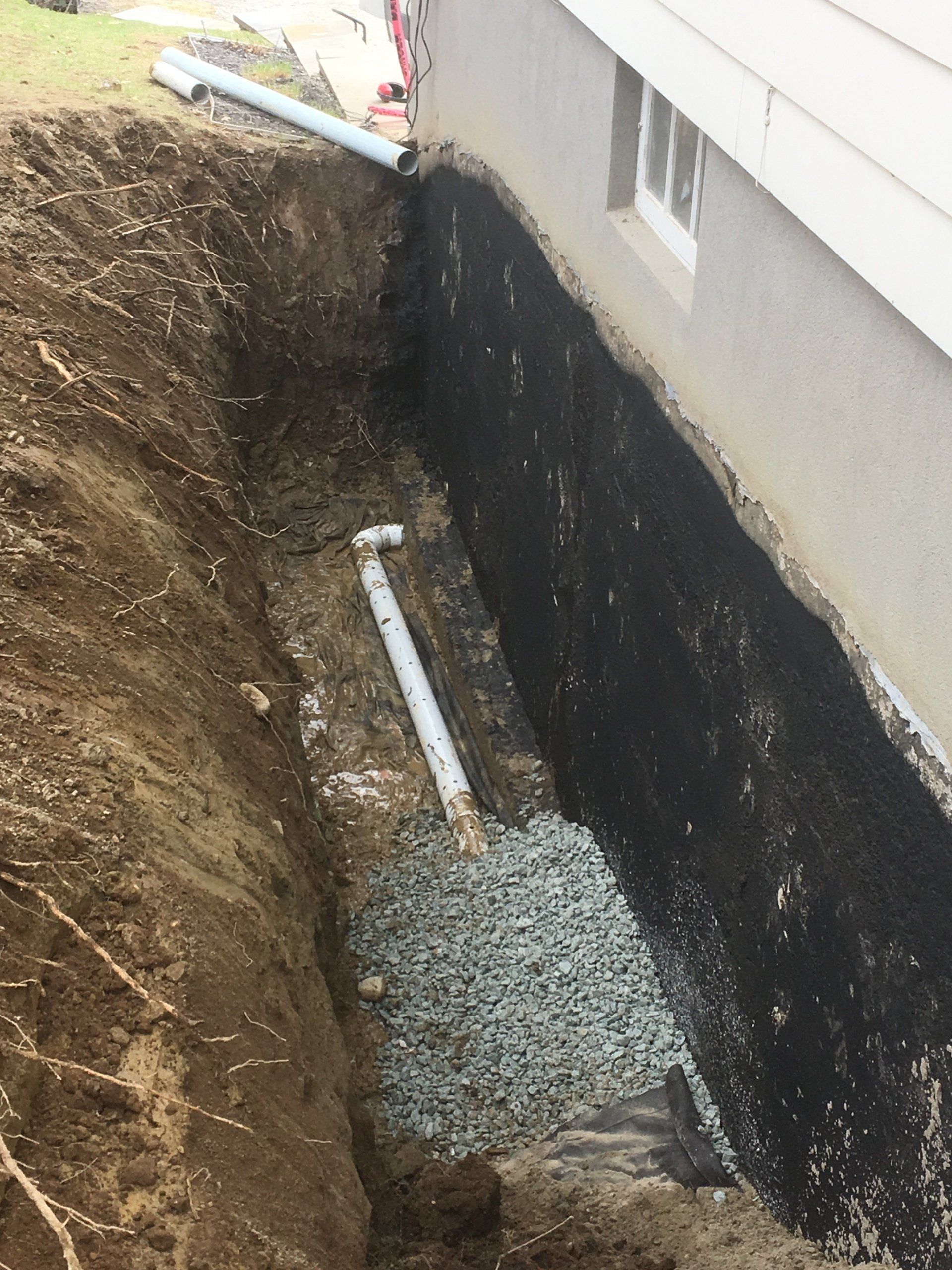 Un système de drainage est en cours d'installation sur le côté d'une maison.