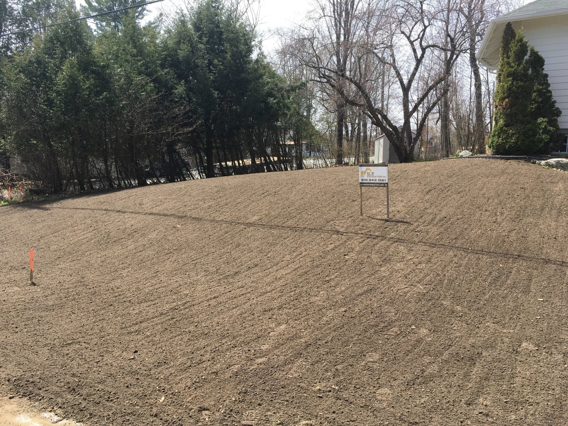 Un champ de terre avec des arbres en arrière-plan et une maison en arrière-plan.