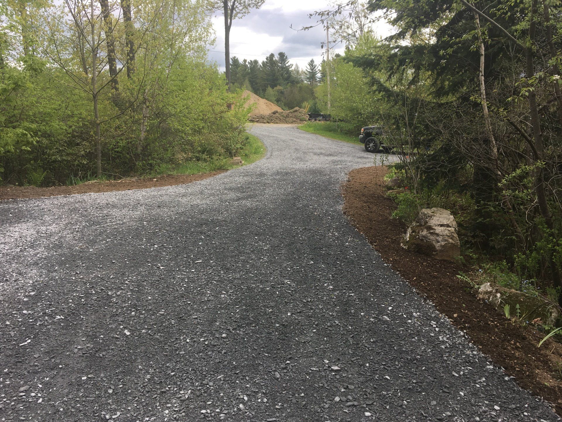 Un chemin de gravier traversant une forêt avec des arbres des deux côtés.