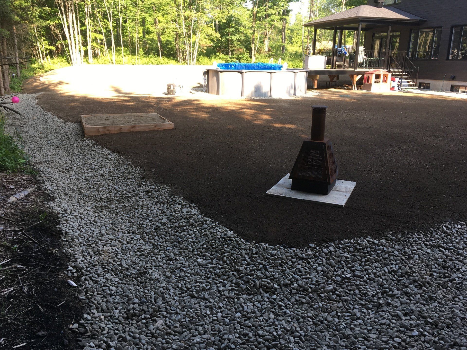 Un foyer est posé sur un tas de gravier dans une cour arrière.