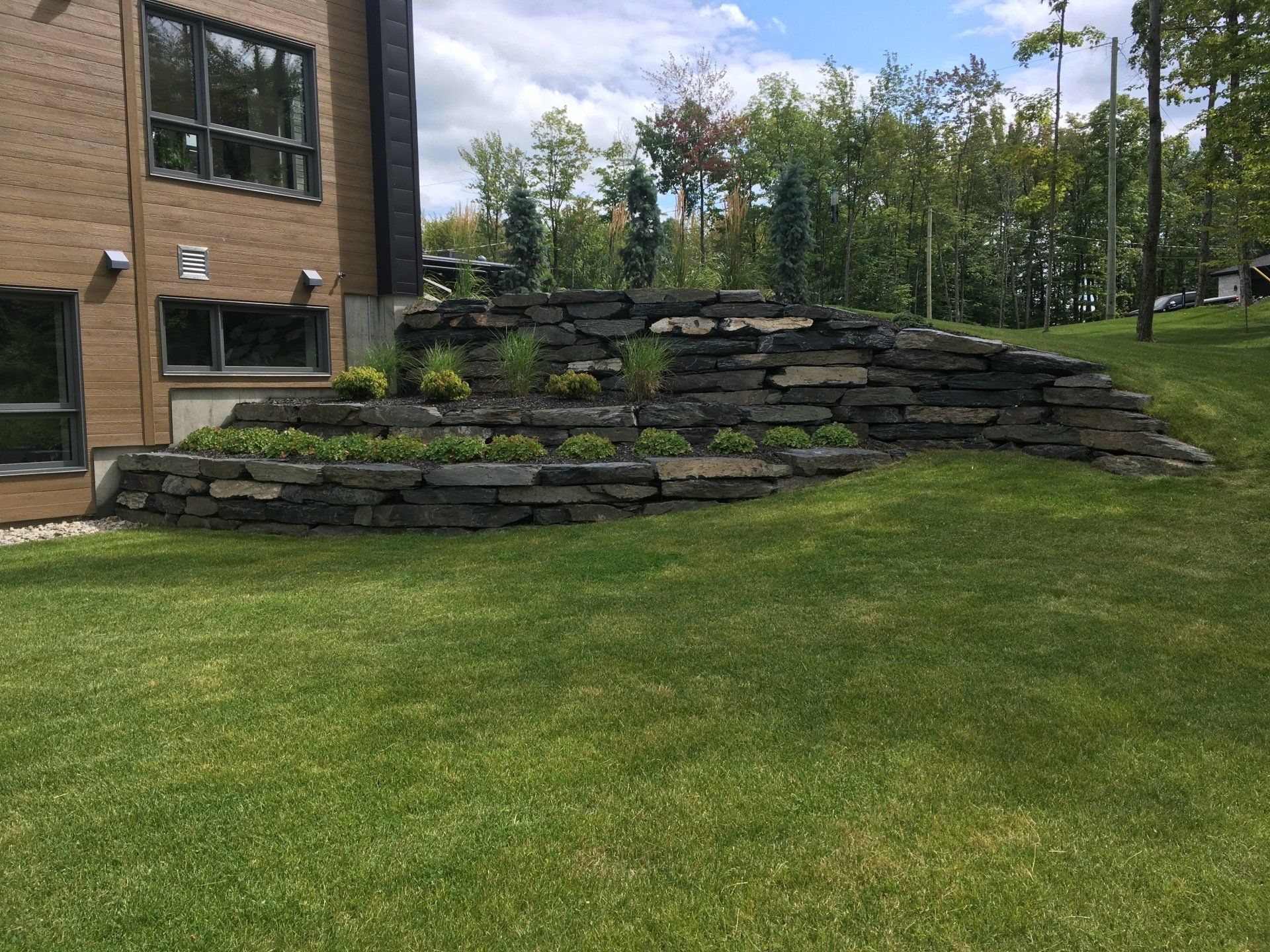 Il y a un grand mur de pierre dans l'arrière-cour d'une maison.