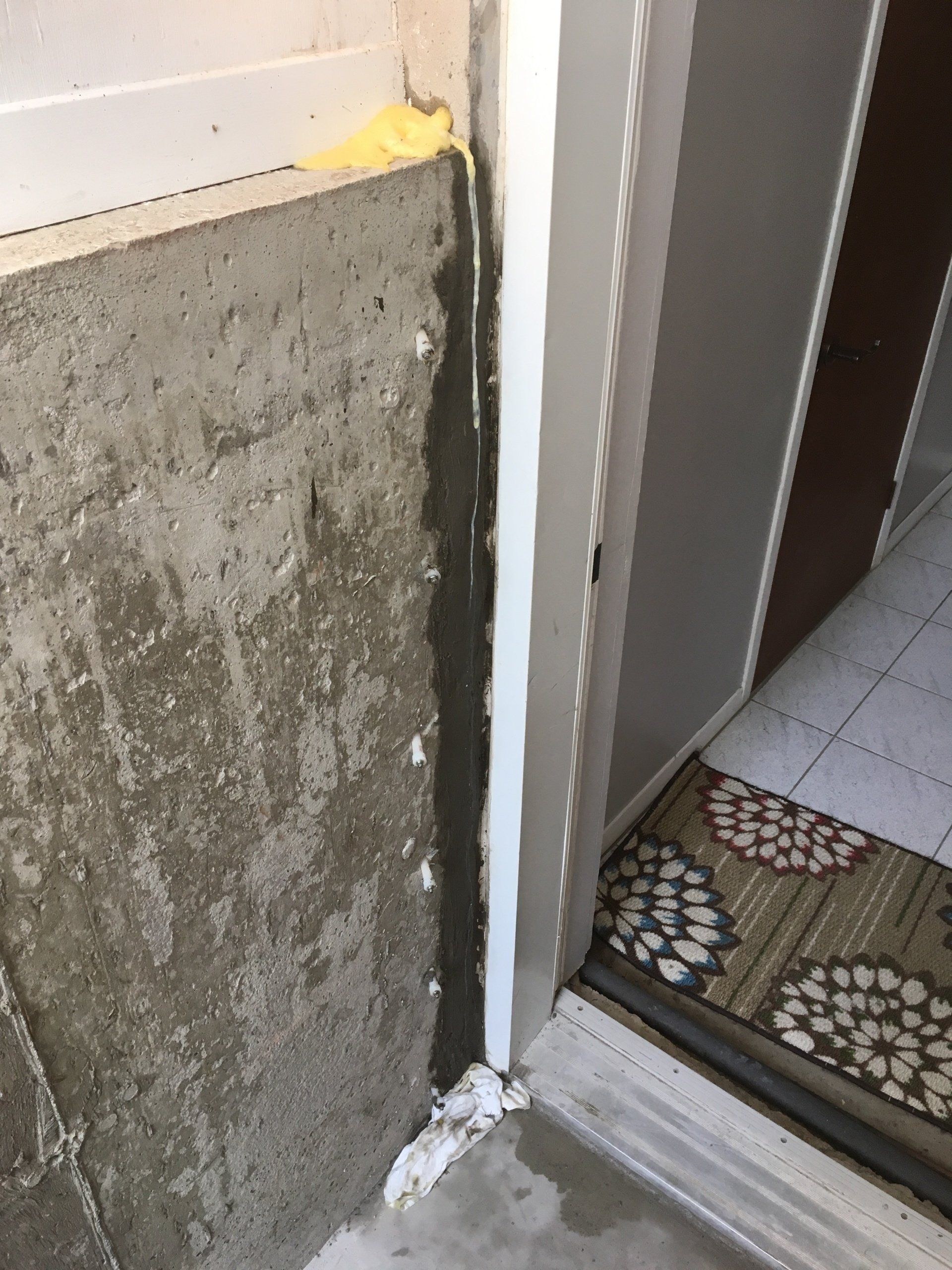 Une porte avec un tapis sur le sol et un mur en béton.