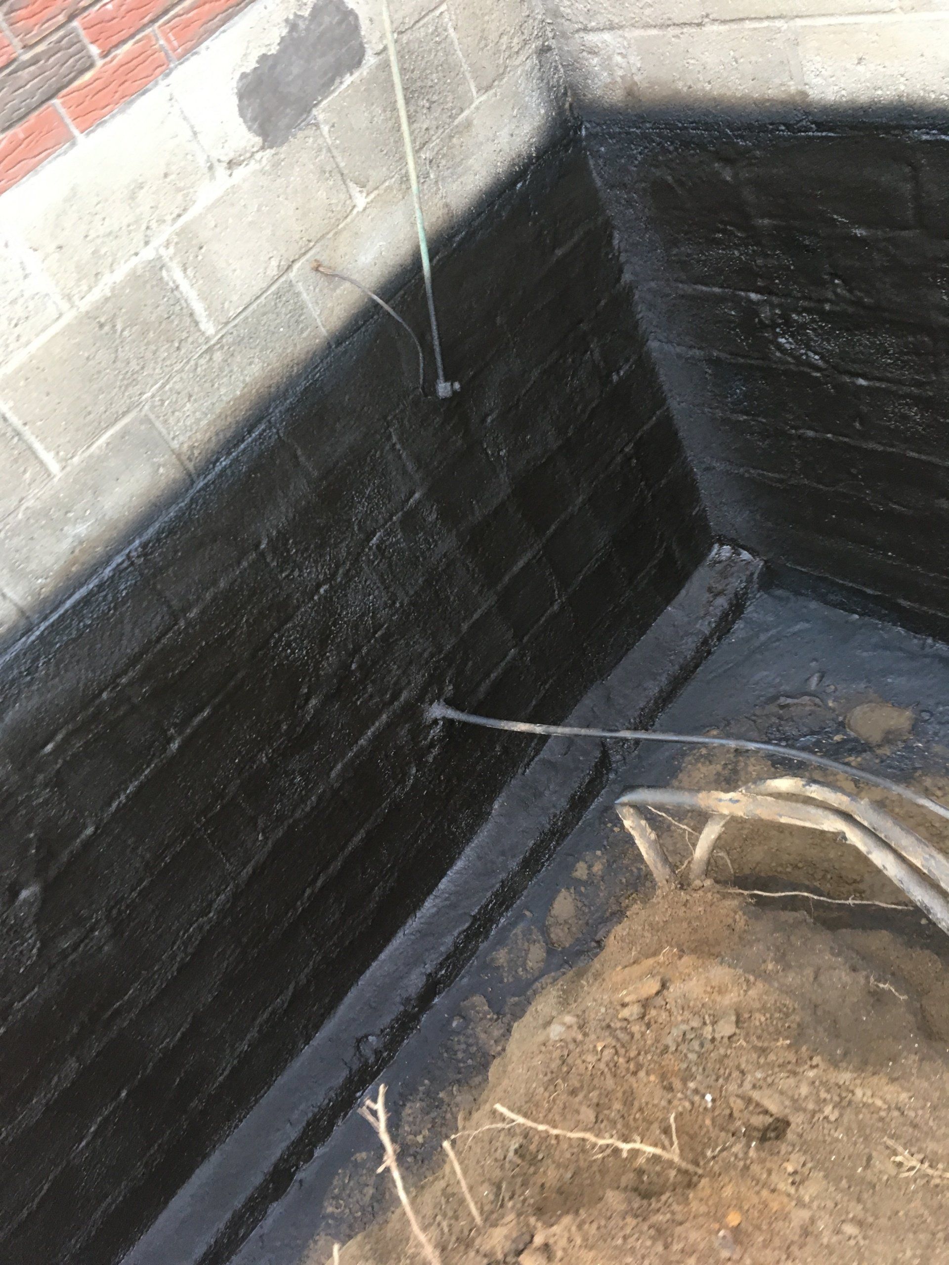 Un mur de briques est peint en noir avec un tuyau.