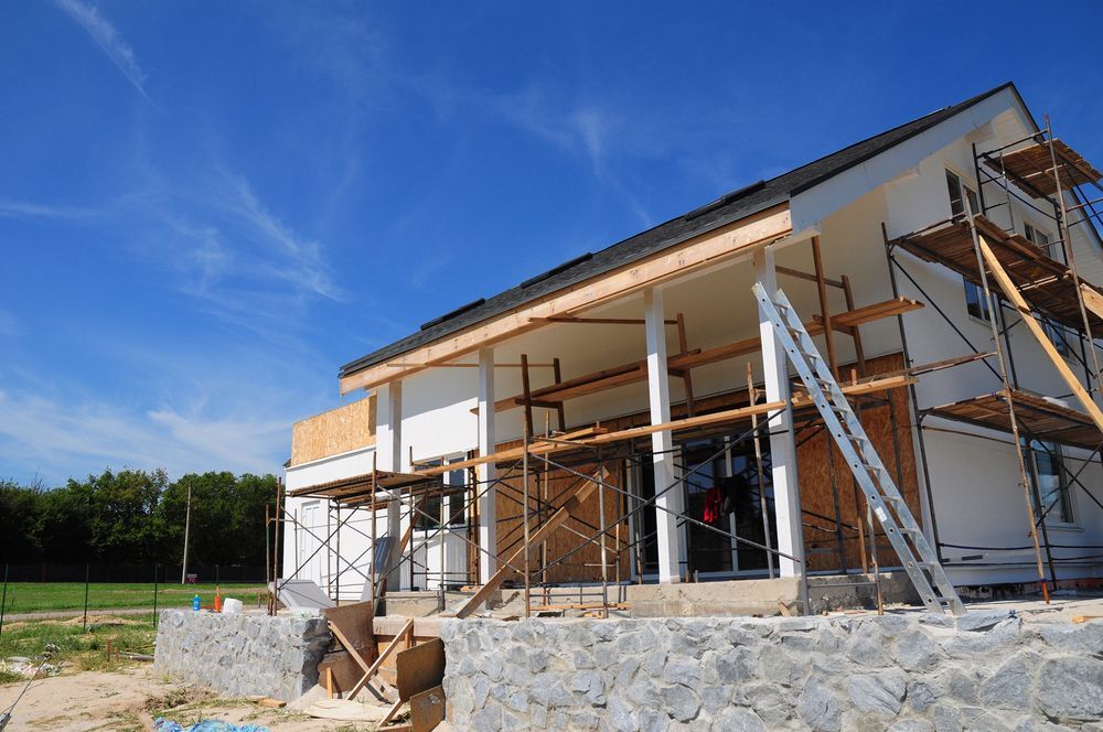 House under construction with scaffolding against a blue sky