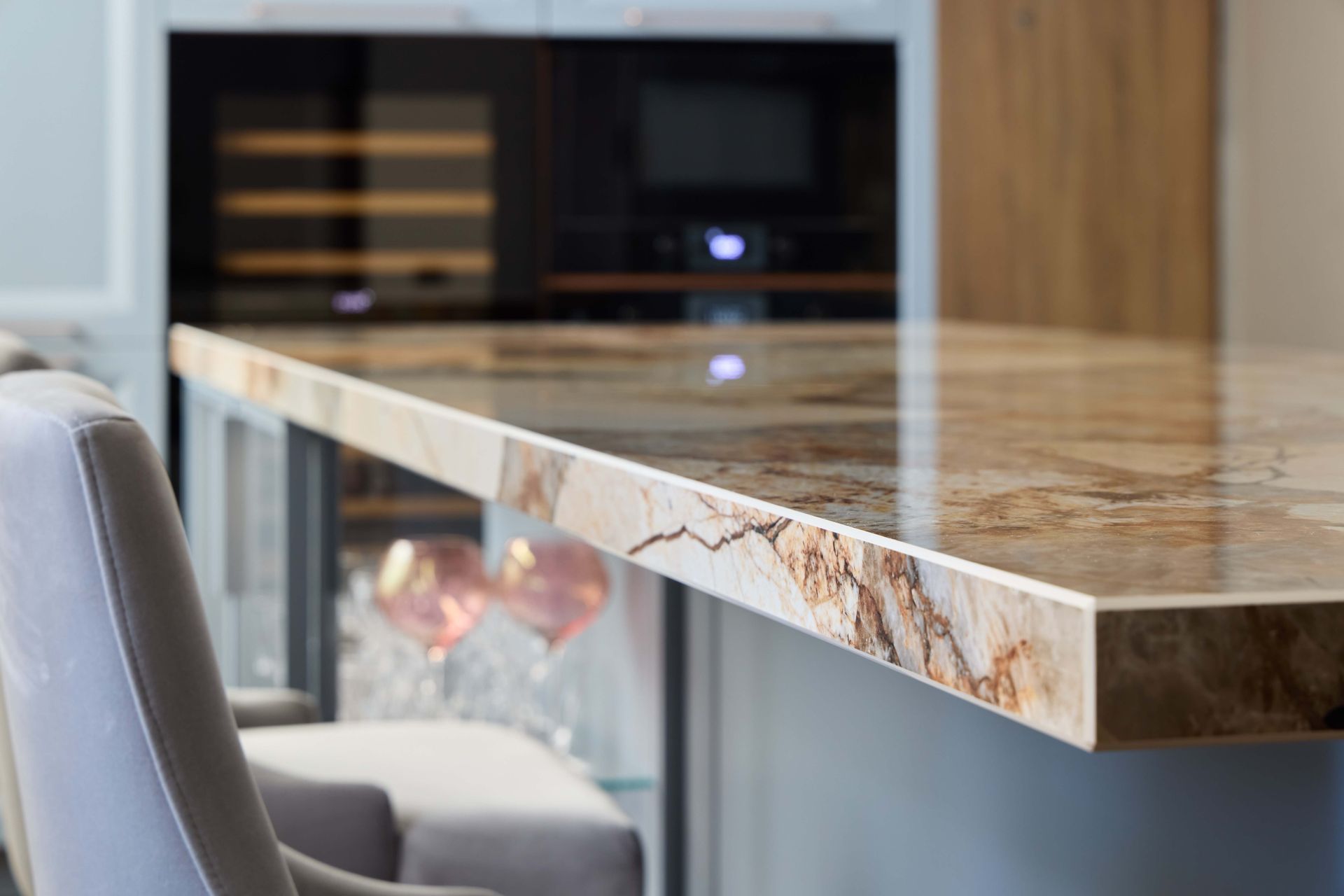 Close-up of a kitchen countertop with a marble pattern and a chair in the foreground.