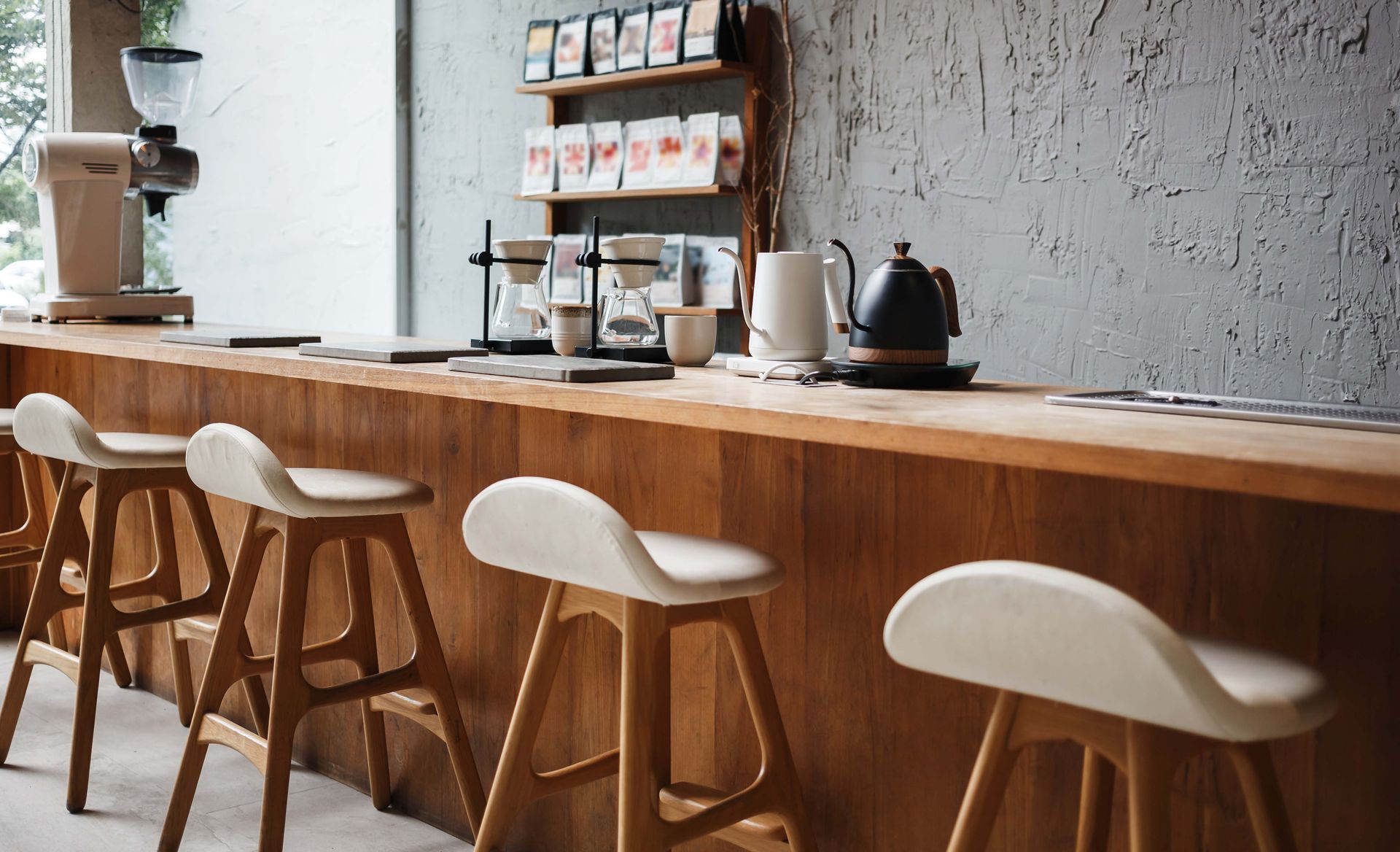 Coffee bar with wooden counter, stools, and brewing equipment.