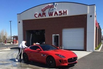 A red sports car being hand-dried at Danny's Car Wash. Two people are working on the car.