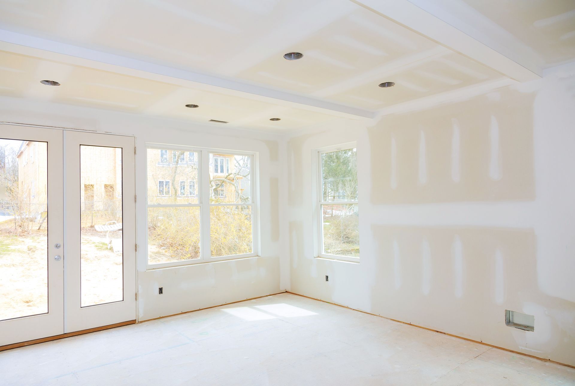 An empty room with a lot of windows and drywall on the walls