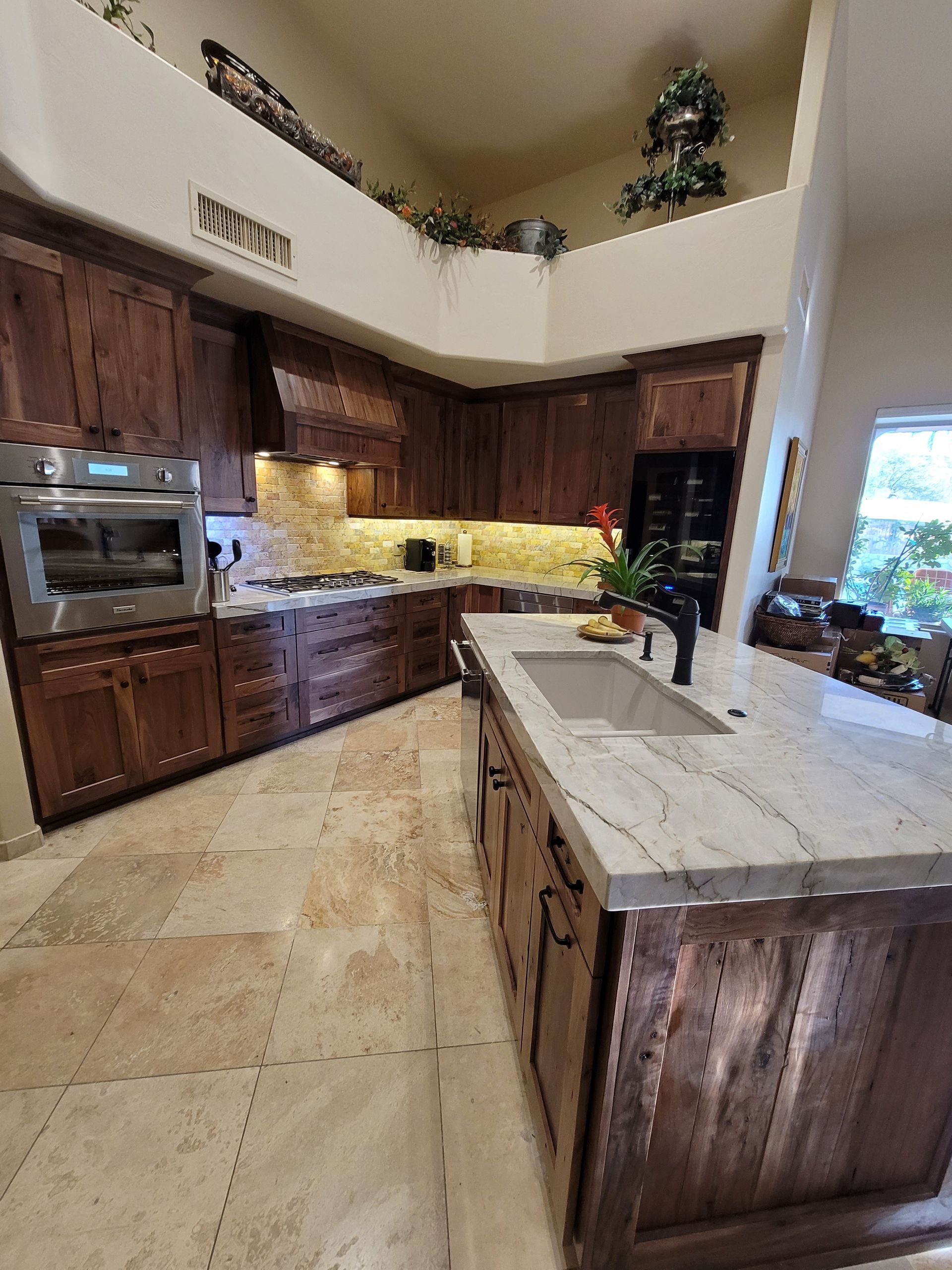 Modern kitchen remodel in [Tucson, AZ] featuring cabinets, waterfall quartz countertops with gold veins, stainless steel appliances (gas range with pot filler faucet, refrigerator, dishwasher, microwave), wood accent breakfast bar, globe pendant lighting.