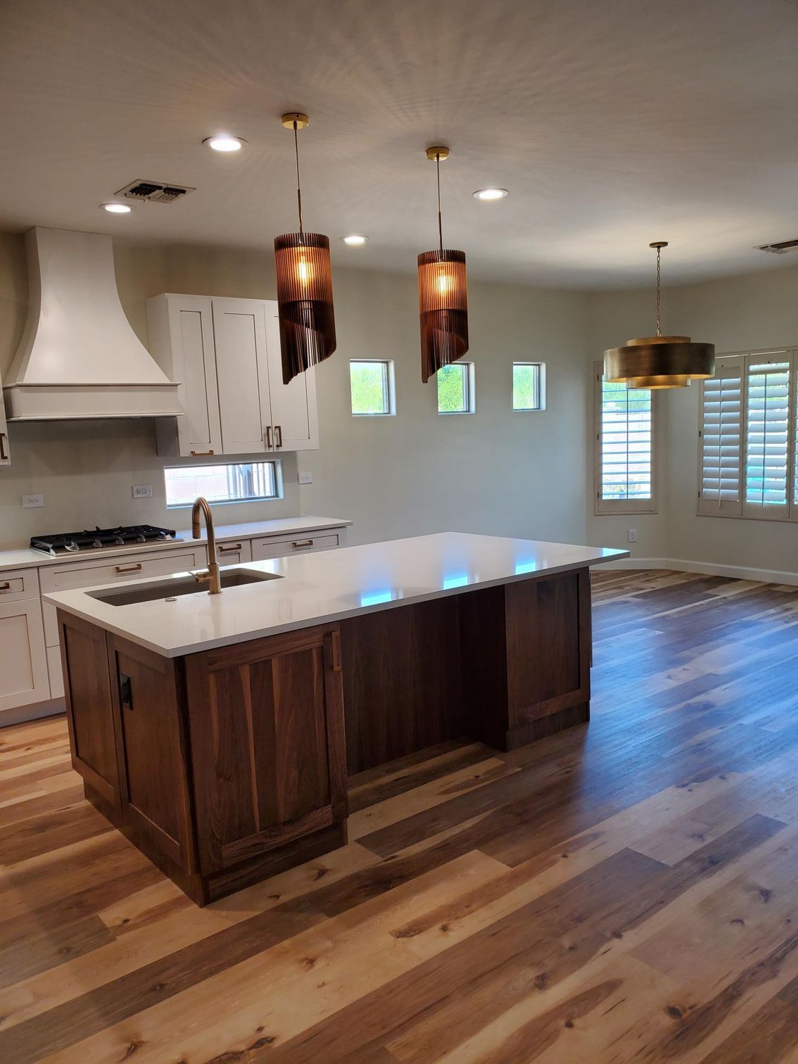 Spacious kitchen featuring breakfast bar, pendant lighting, white shaker cabinets, granite countertops, and hardwood flooring. Perfect for modern living. 