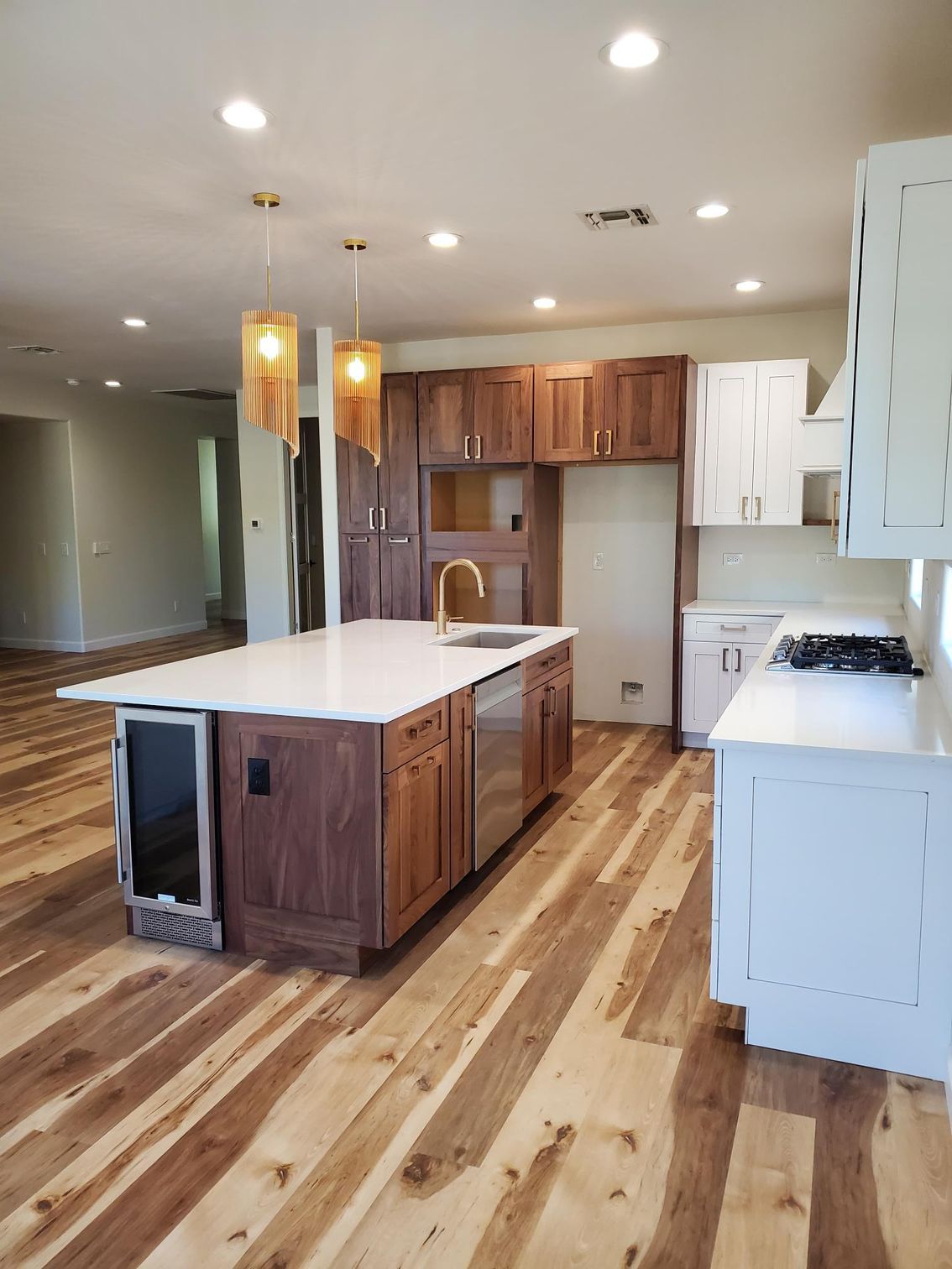 Beautifully remodeled kitchen featuring wood flooring, large white island countertop, modern pendant