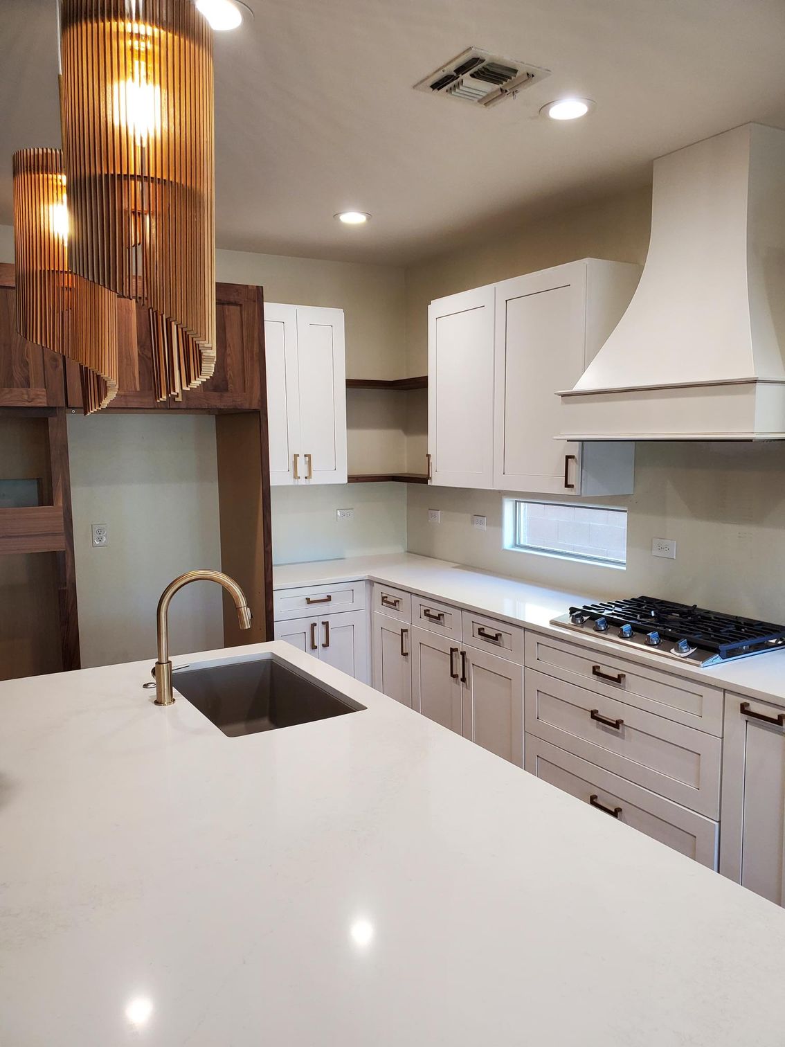 Modern kitchen remodel featuring white shaker cabinets, waterfall quartz countertops with soft veining, and stainless steel appliances.