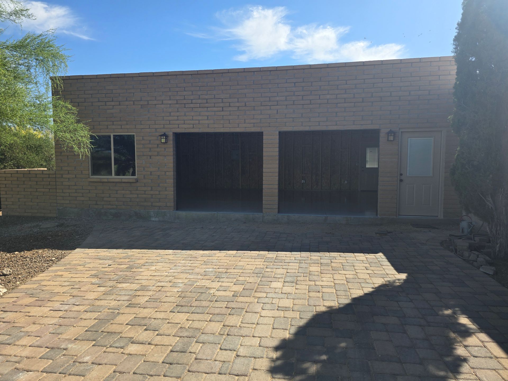 A two-car garage made of brick with a side door on the right and a window on the left.