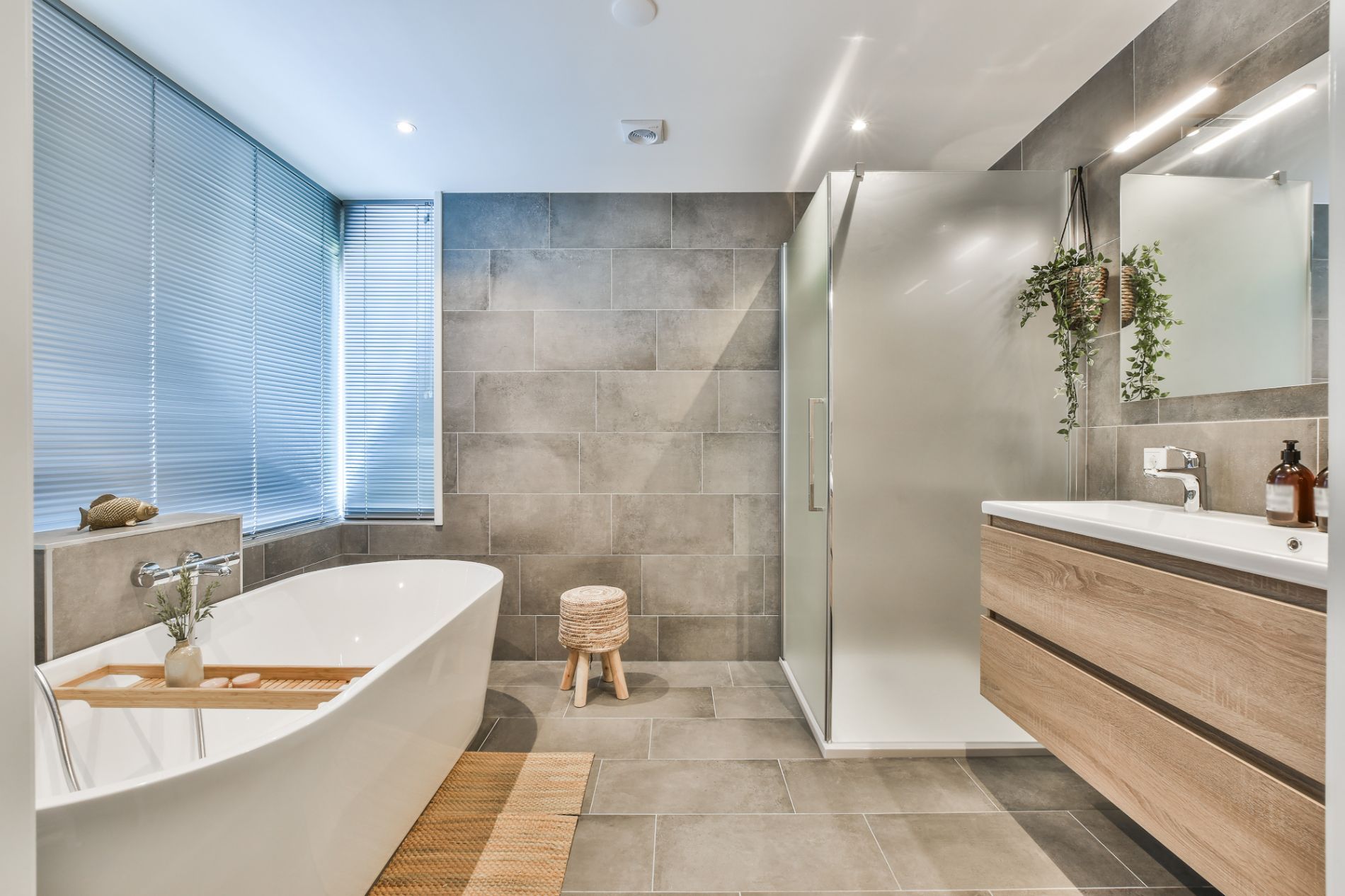 A bright and modern bathroom with a large bathtub, a walk-in shower with a glass door, and a single 