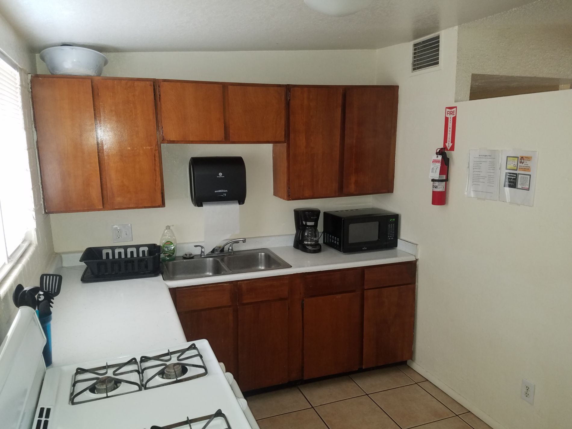 Kitchen with dated appliances (stove, sink, microwave) and brown cabinets, ready for a modern remodel in (Tucson AZ)