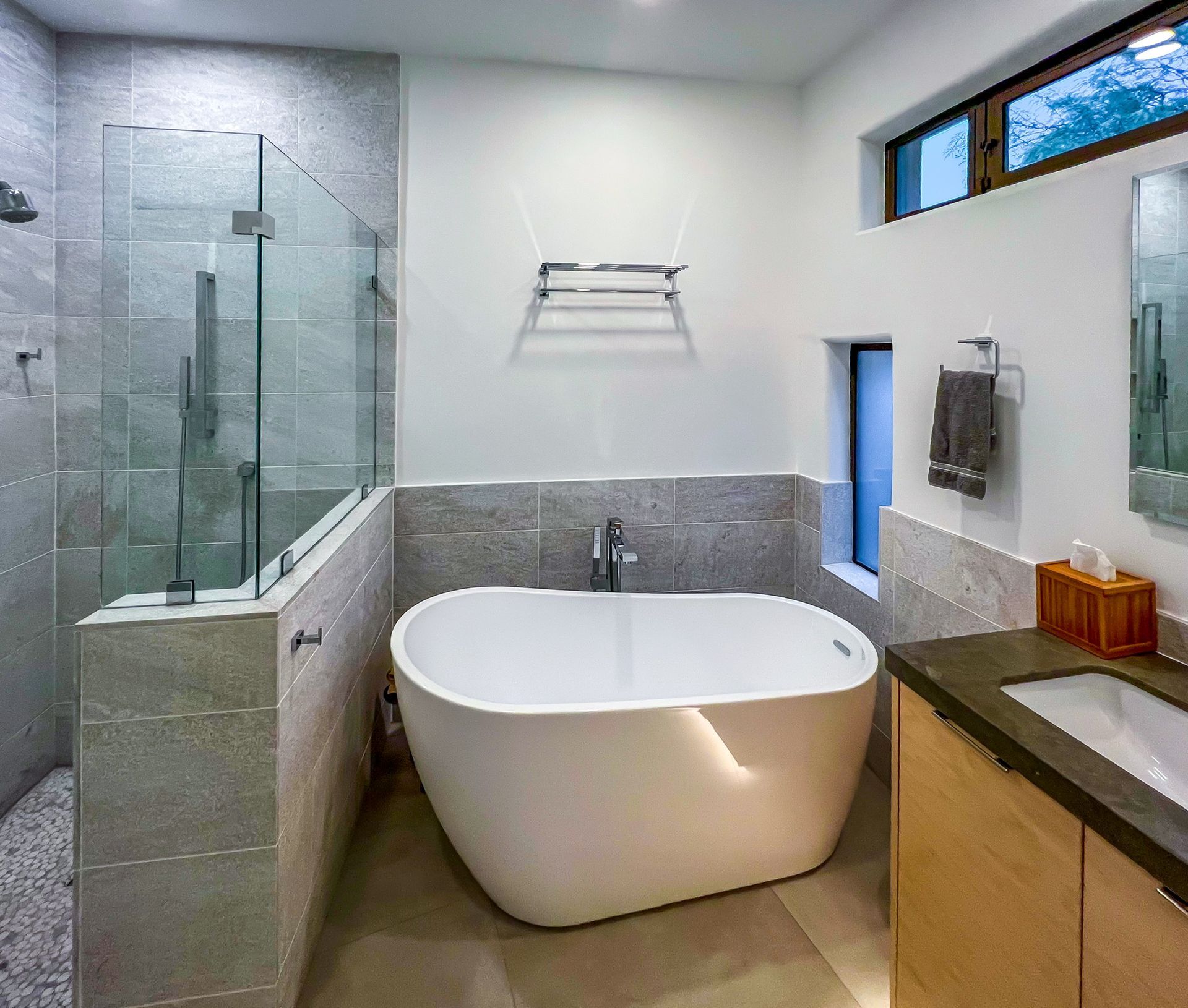 A freestanding sinker tub with tiled flooring.