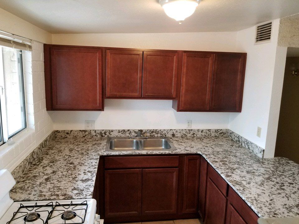 Kitchen with updated appliances (stove, refrigerator, dishwasher) and brown cabinets in [Tucson, Arizona], 
