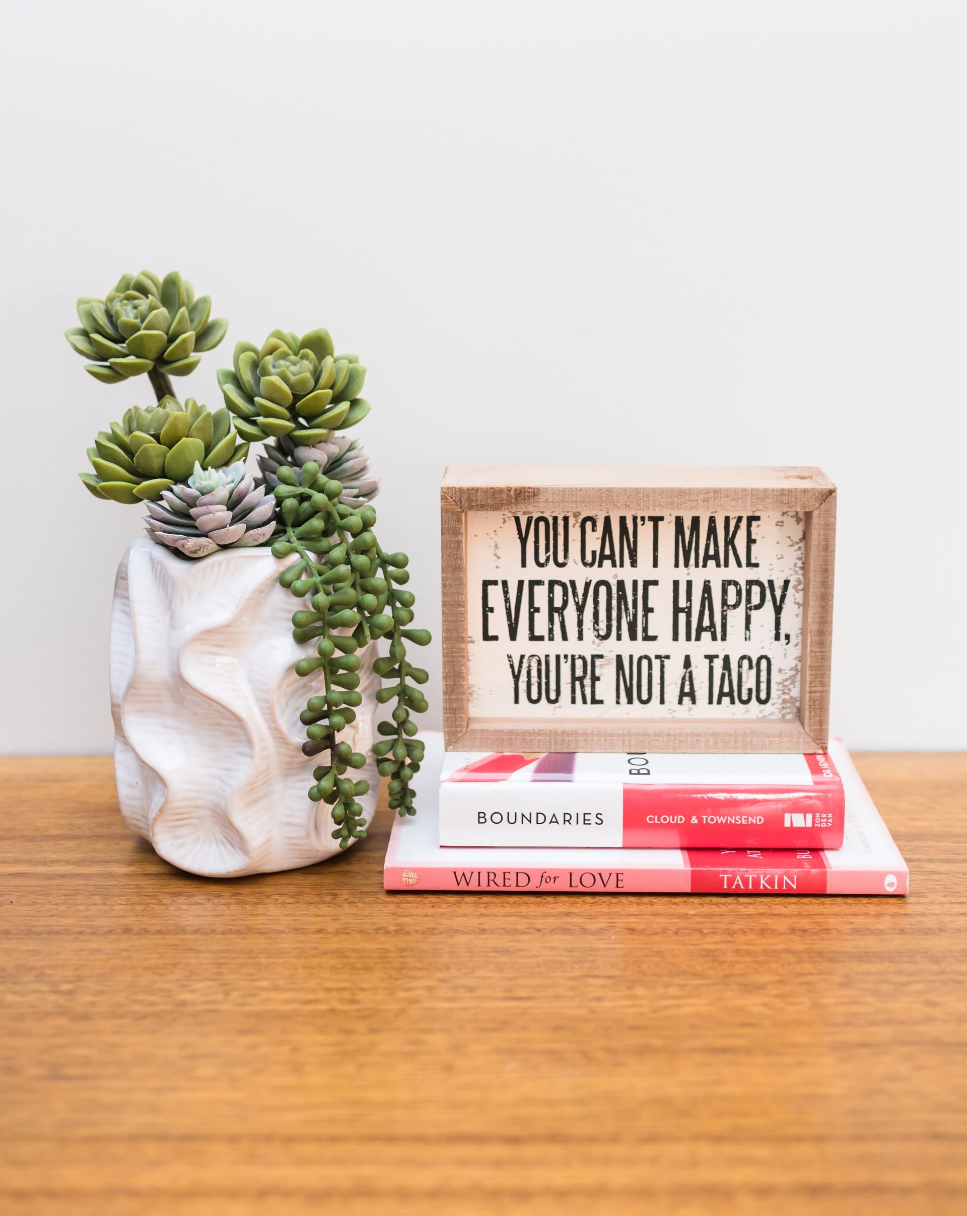 Succulents in white pot, sign says 