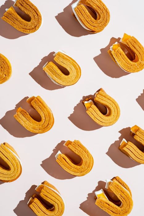 U-shaped layered pastries on a pink surface, casting shadows.