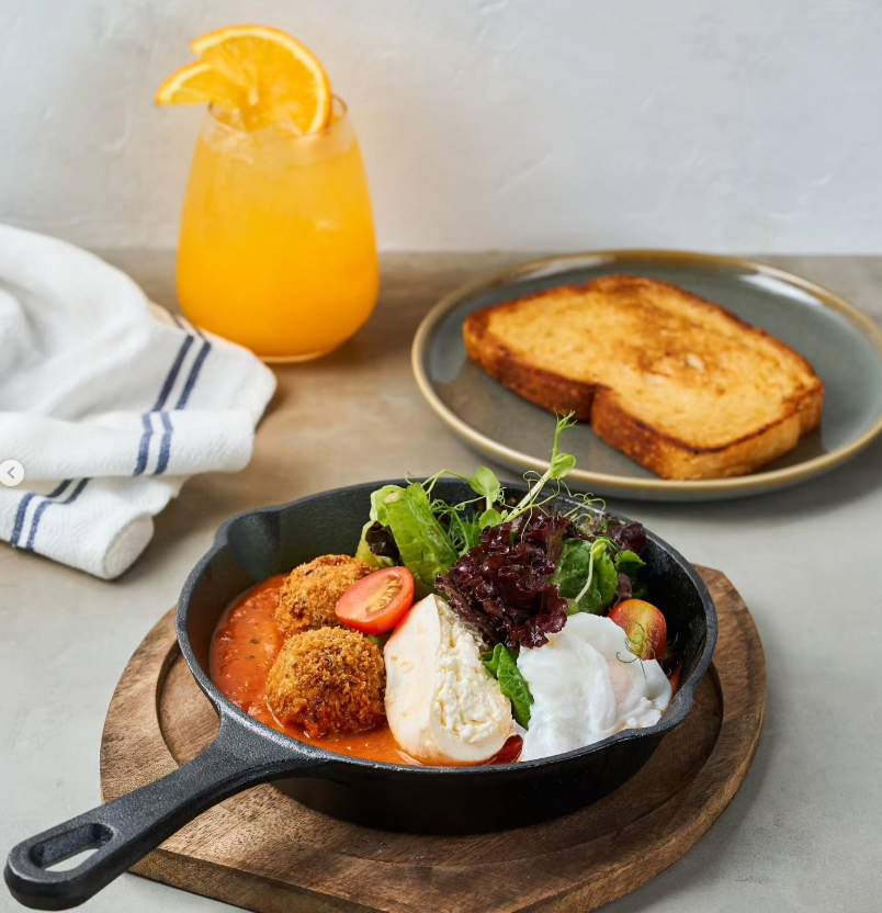 Breakfast plate with meatballs, salad, toast, and orange juice.