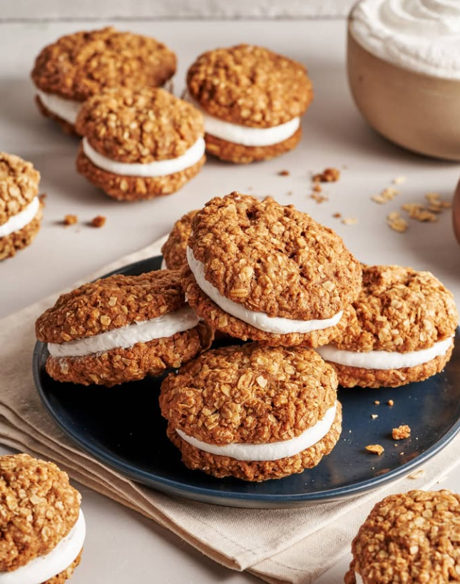 Oatmeal cream pies on a blue plate. Oatmeal cookies with white filling, arranged on a table.