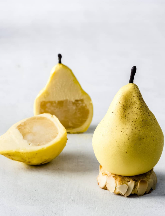 Three pear-shaped desserts: one whole on a base, one cut in half, and one piece cut off. Yellow exterior, tan interior.