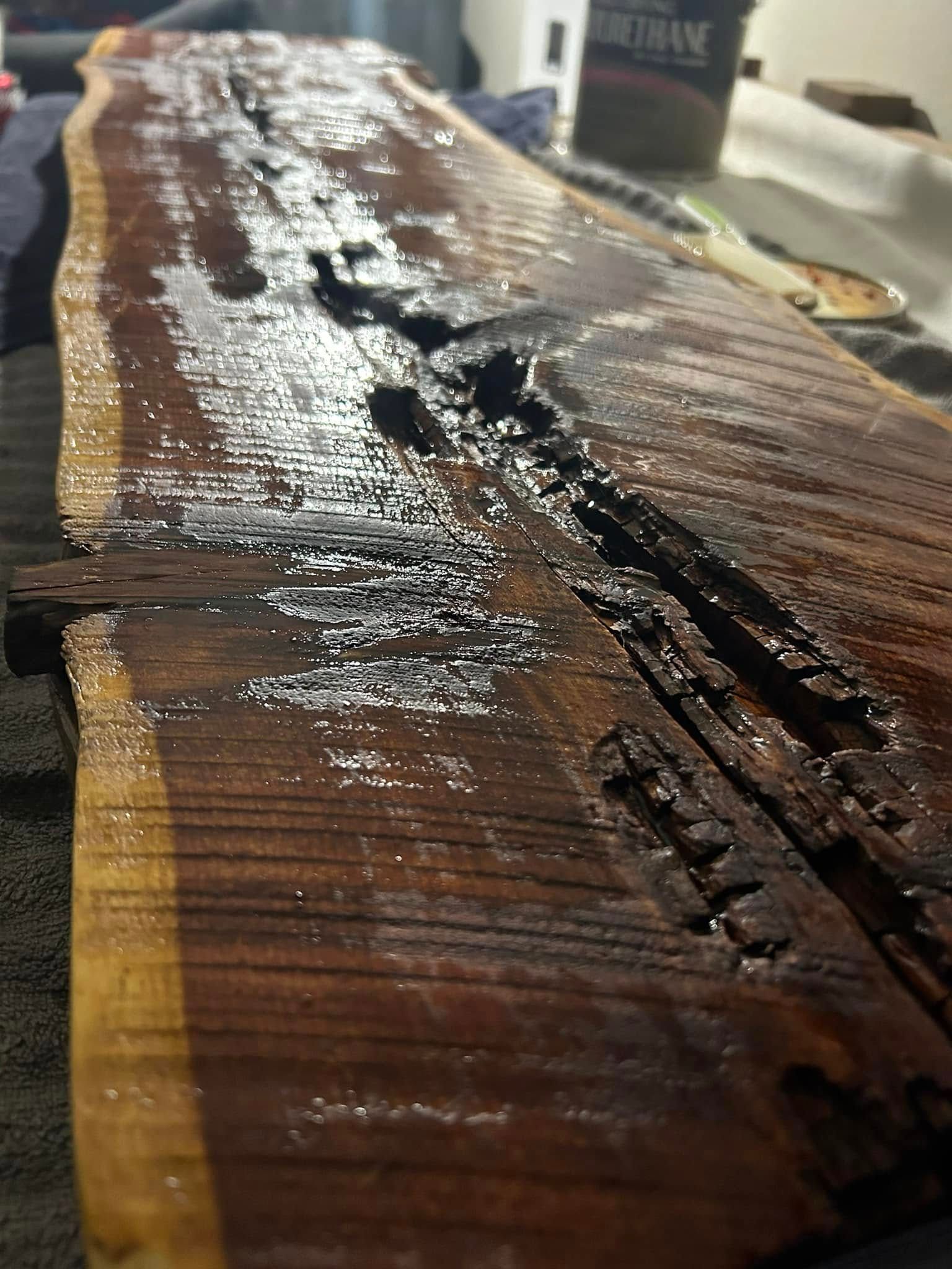 Wood slab with glossy finish. Brown wood with cracks and knots, light reflecting.