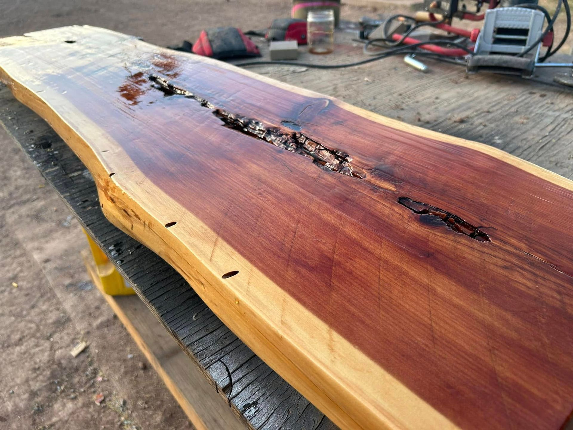Wooden slab with a dark crack running through the middle, finished with a reddish stain.