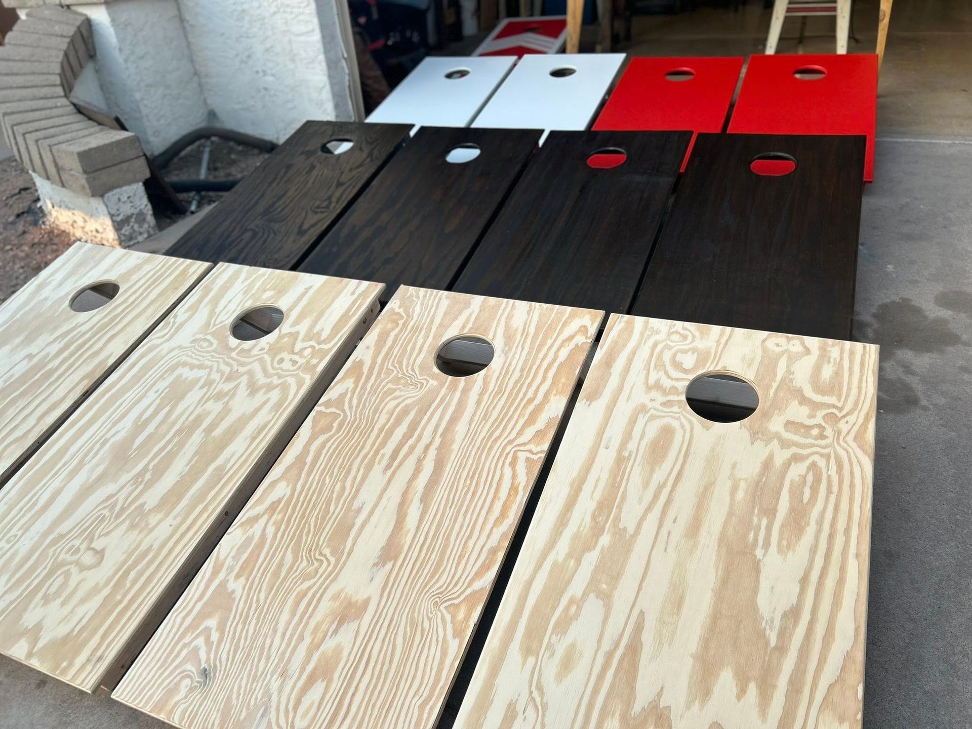 Cornhole boards: six wooden boards in various colors, lined up in an outdoor setting.