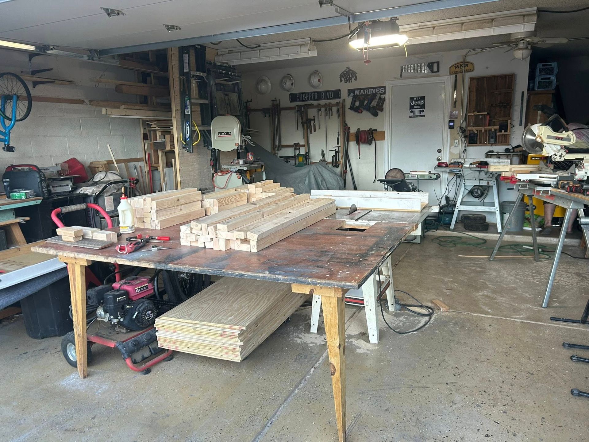 Workshop with a workbench covered in wood planks and tools, cluttered garage.