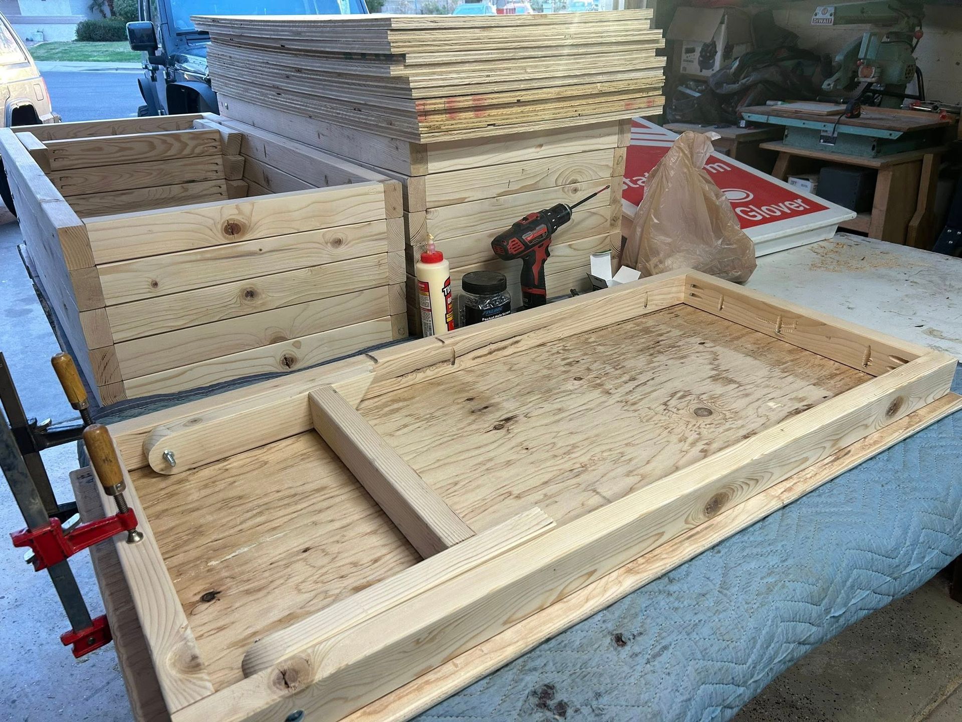 Wooden boxes and frames being constructed on a table in a garage, with tools and materials nearby.
