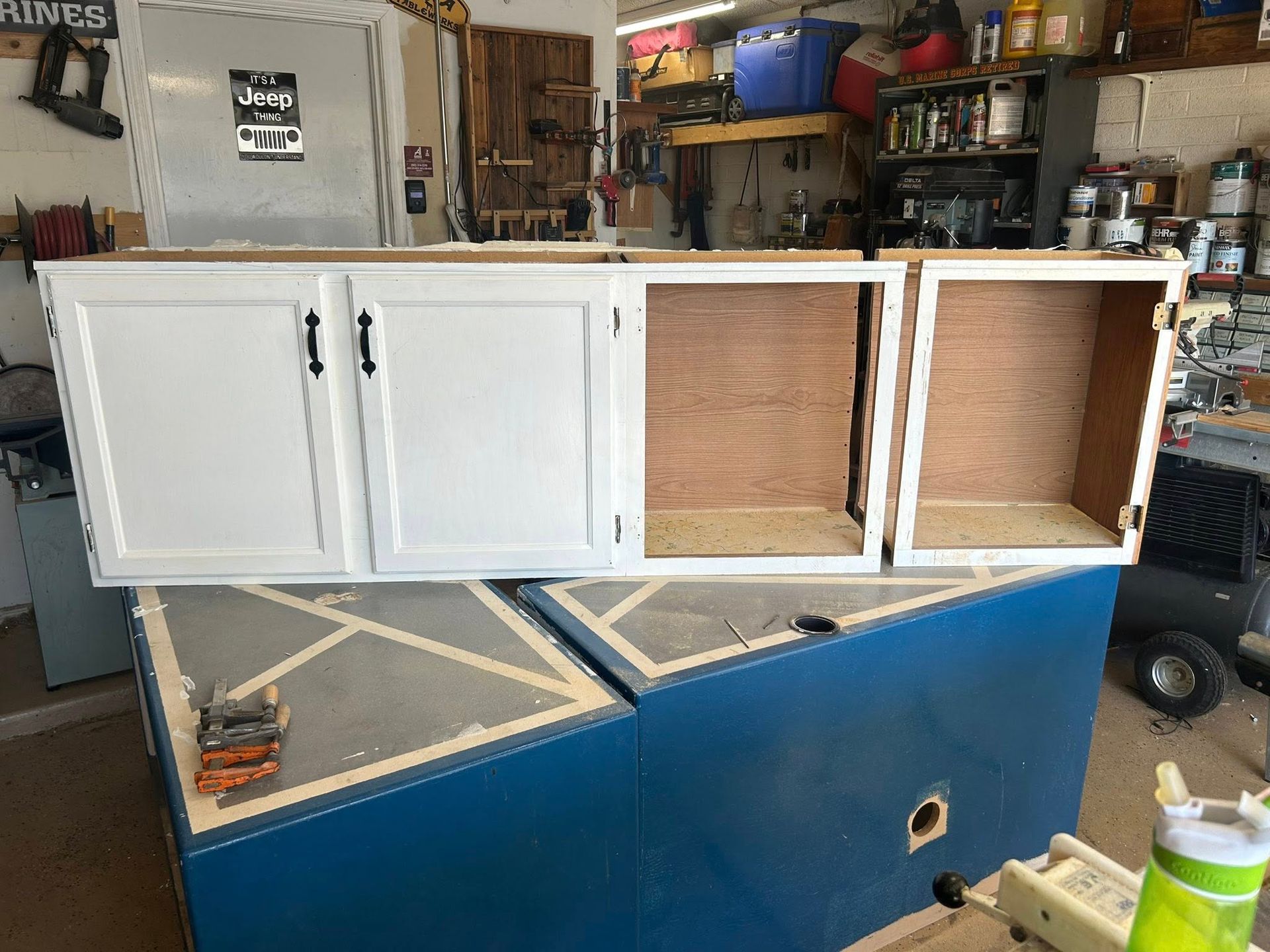 White cabinet sections on blue surface in workshop setting.