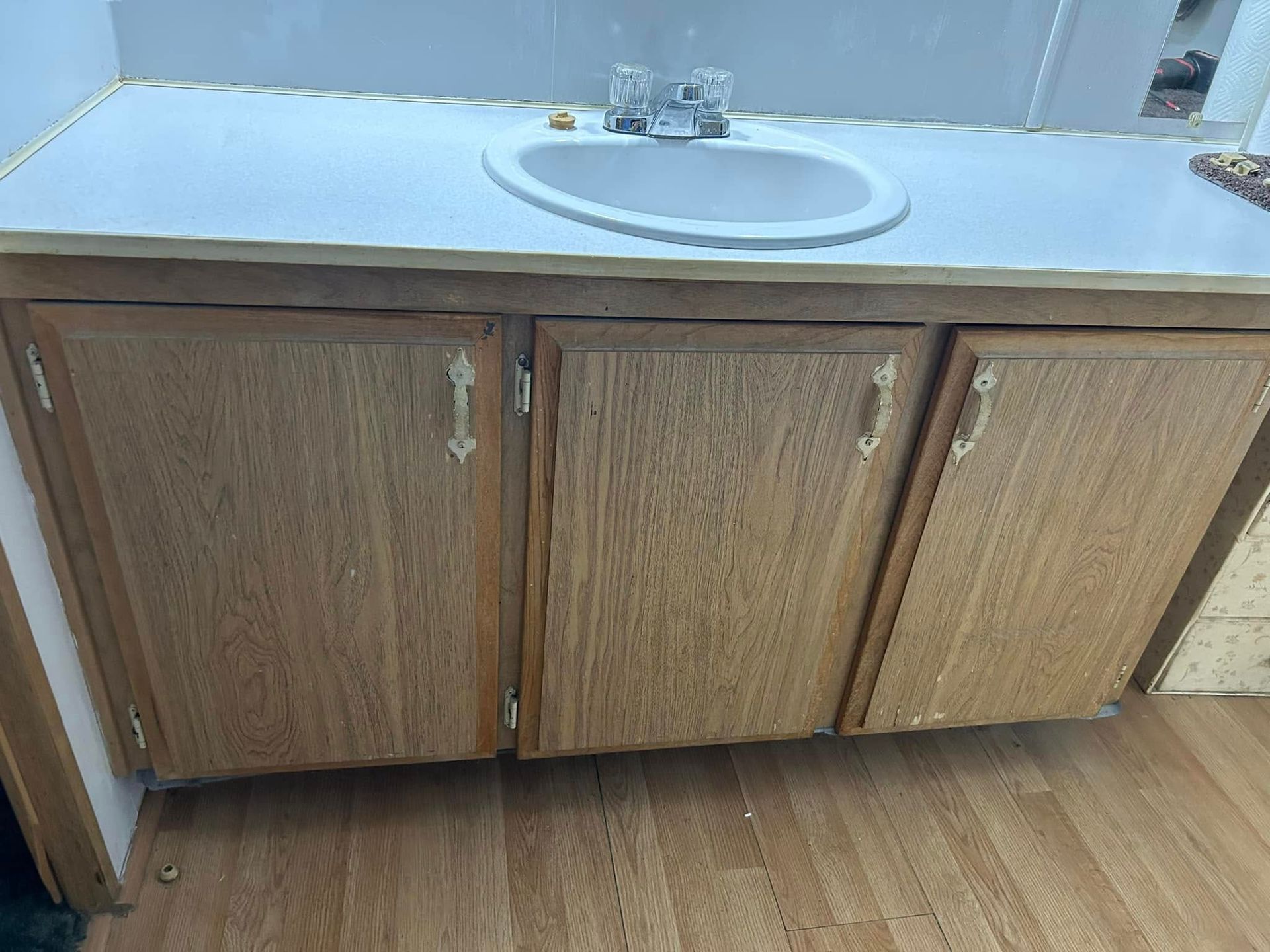 Bathroom vanity with wooden cabinets, a white sink, and a white countertop.