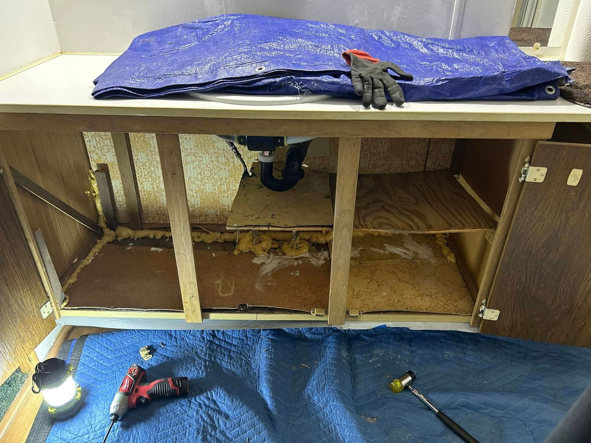 Interior of cabinet being worked on with tools, tarp, and protective coverings.