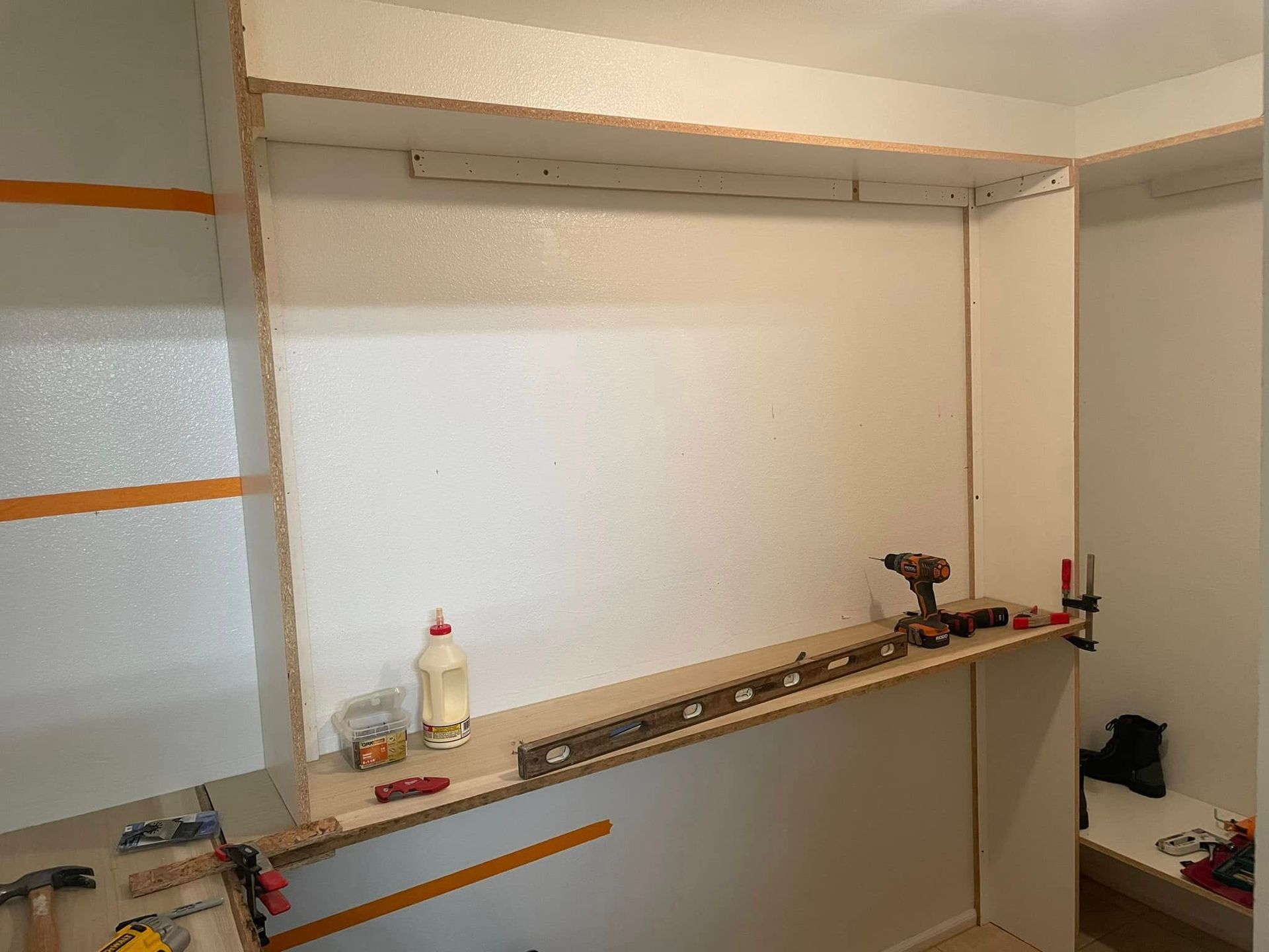 Construction of a closet; a workspace with tools and materials: wood, glue, drill.