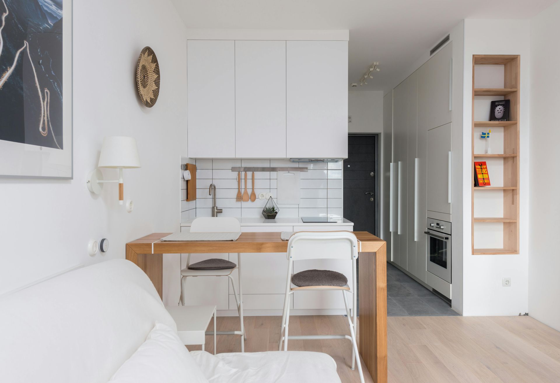 Small, modern kitchen with white cabinets, wooden countertops and two bar stools.