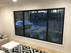 Living room with large black-framed windows; a car is visible outside.