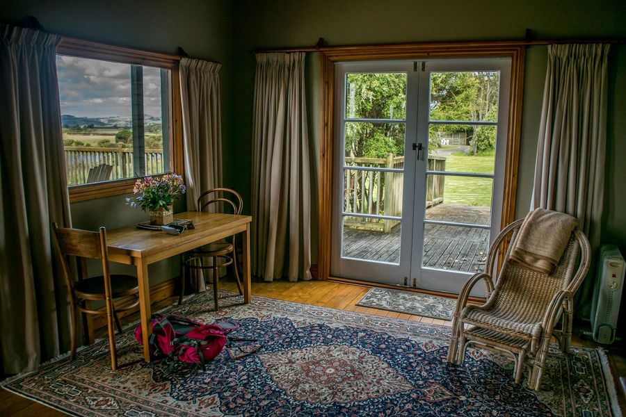 Cozy room with a table by a window, a rug, a chair, and french doors opening to a green yard.