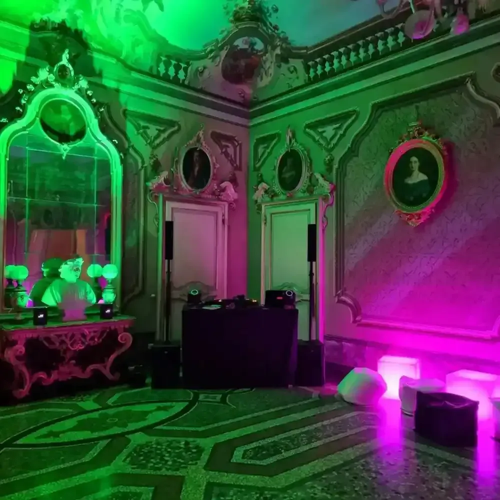 Stanza riccamente illuminata con luci al neon verdi e rosa, uno specchio, ritratti e motivi decorativi sul pavimento.