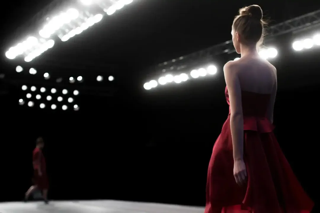 Ballerina in abito rosso su un palcoscenico scarsamente illuminato con luci brillanti dall'alto