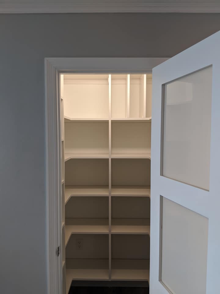 A walk in closet with shelves and a glass door.