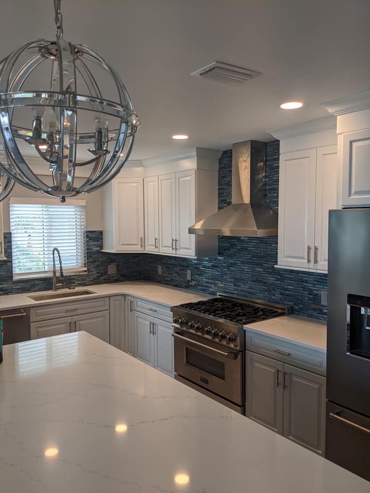 A kitchen with white cabinets , stainless steel appliances , and a large island.