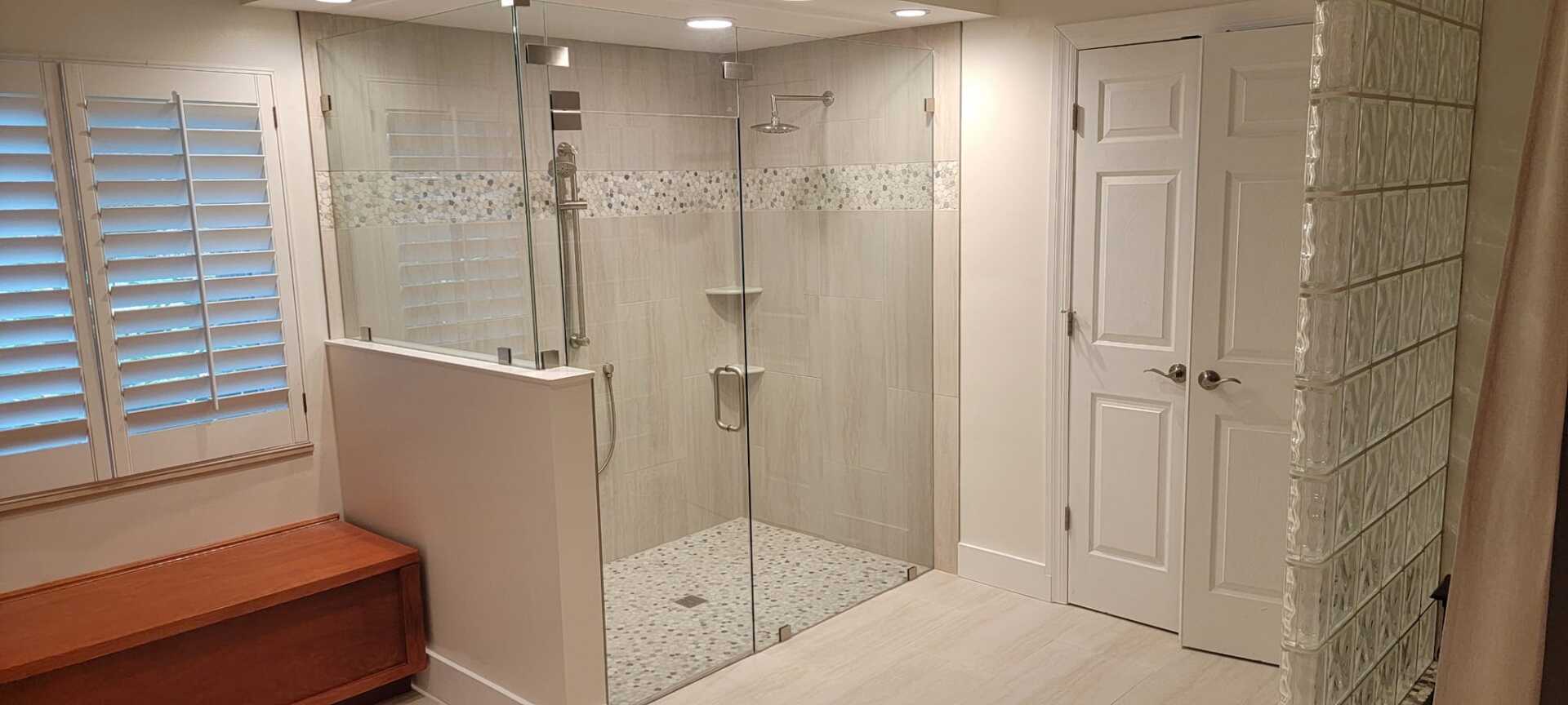 A bathroom with a walk in shower and a bench.