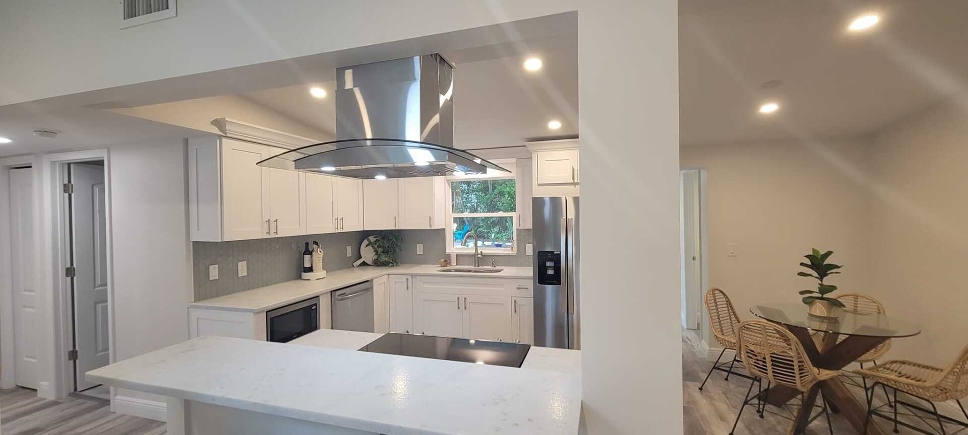 A kitchen with white cabinets , stainless steel appliances , a stove top oven and a refrigerator.