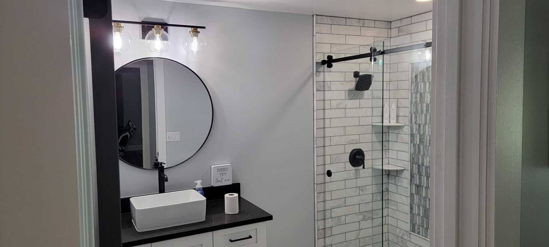 A bathroom with a sink , mirror , and shower.