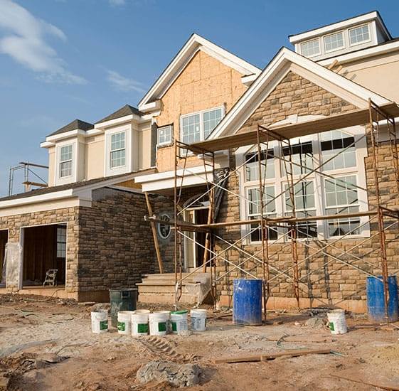 A house under construction with buckets of paint in front of it