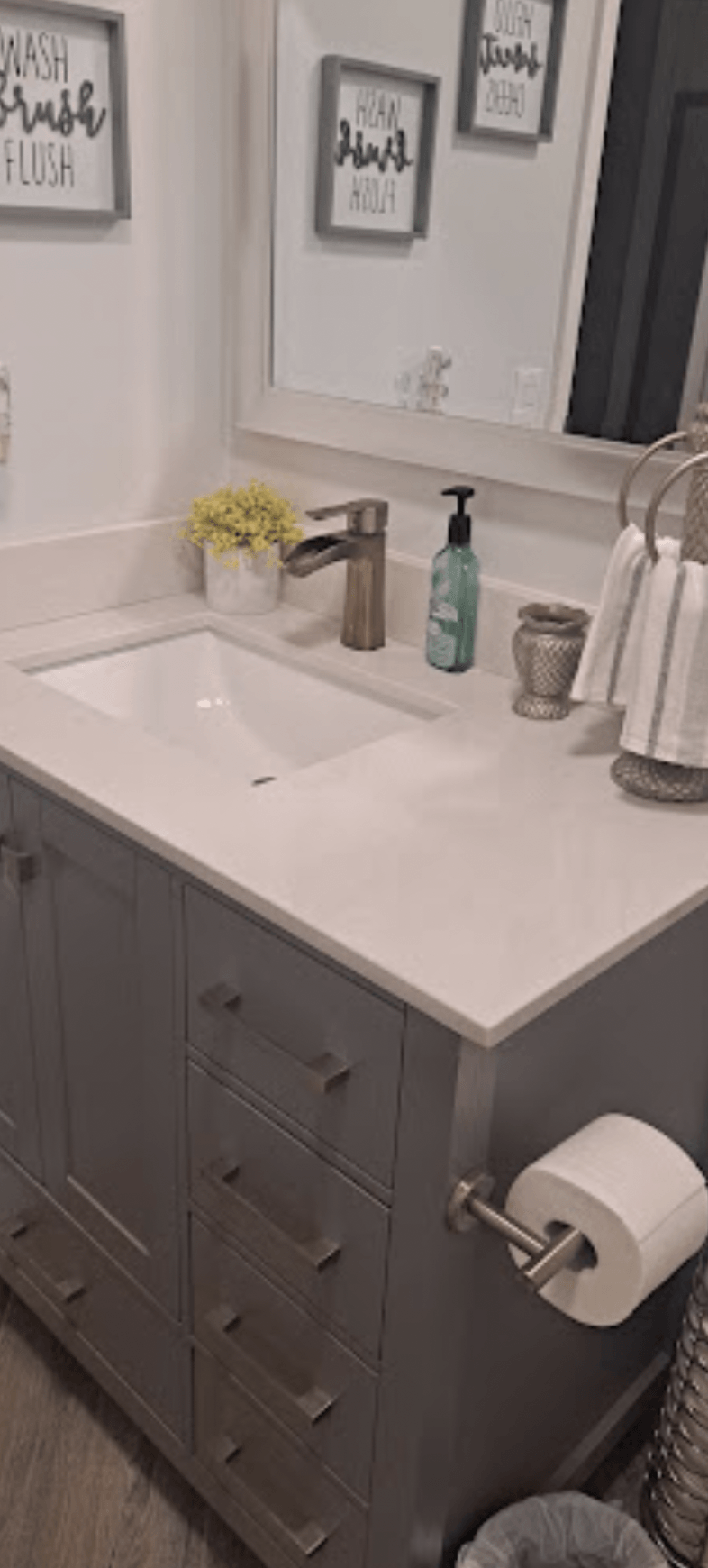 A bathroom with a sink , mirror and toilet paper.