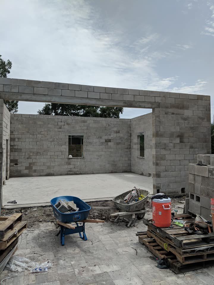 A wheelbarrow is sitting in front of a building under construction.