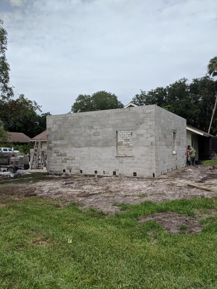 A large brick building is being built in a grassy field.