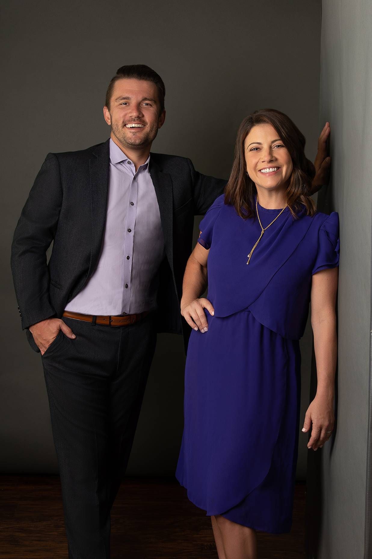 A man in a suit and a woman in a blue dress are standing next to each other.